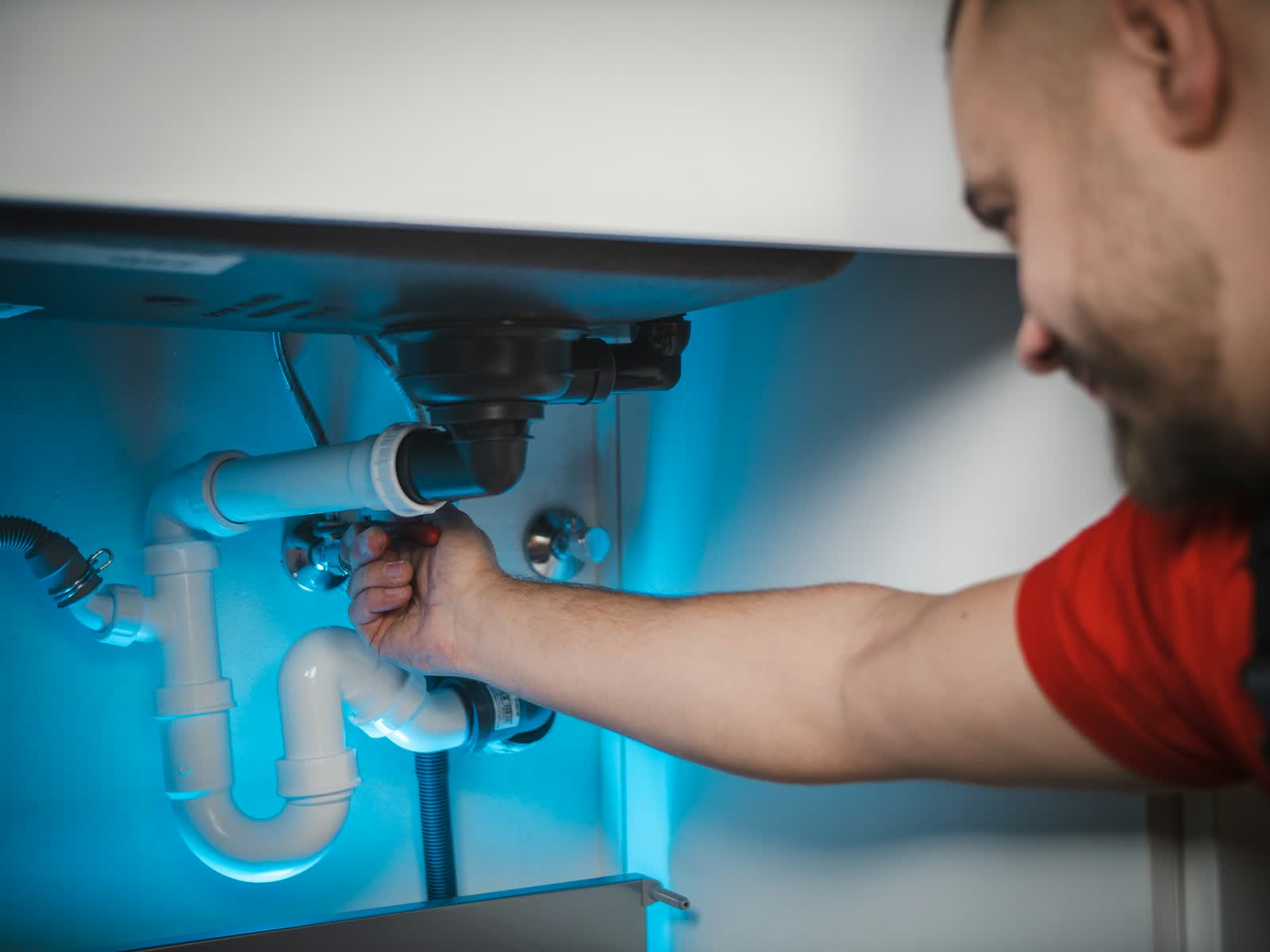Brightwater plumber fixing the pipes under a kitchen sink