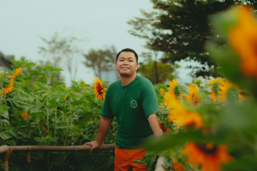 Sam Tran, owner of Fieldwork, standing in a sunflower garden